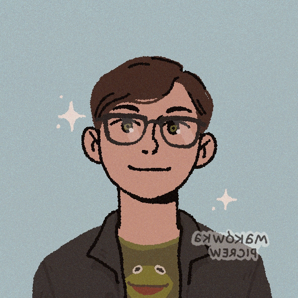 A dark-haired man wearing rectangular glasses, a frog t-shirt, and black jacket+beanie
